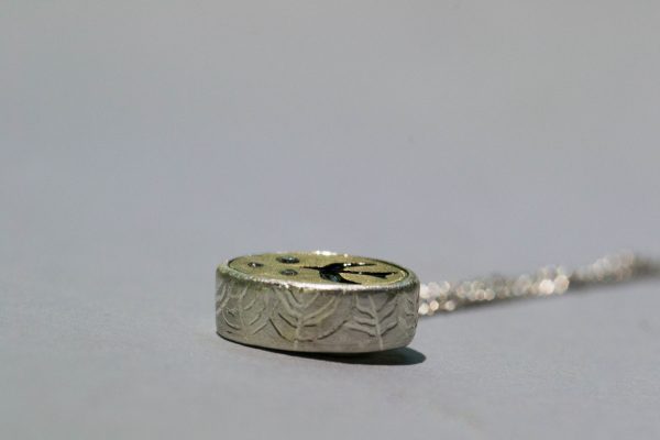 Engraved side of bezel on necklace on grey